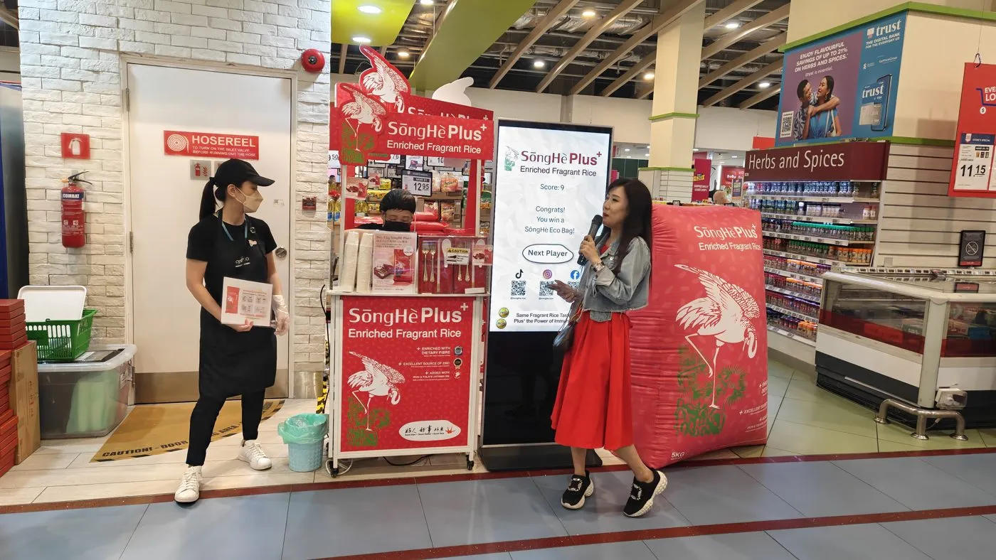 A supermarket roadshow booth with a host and shoppers